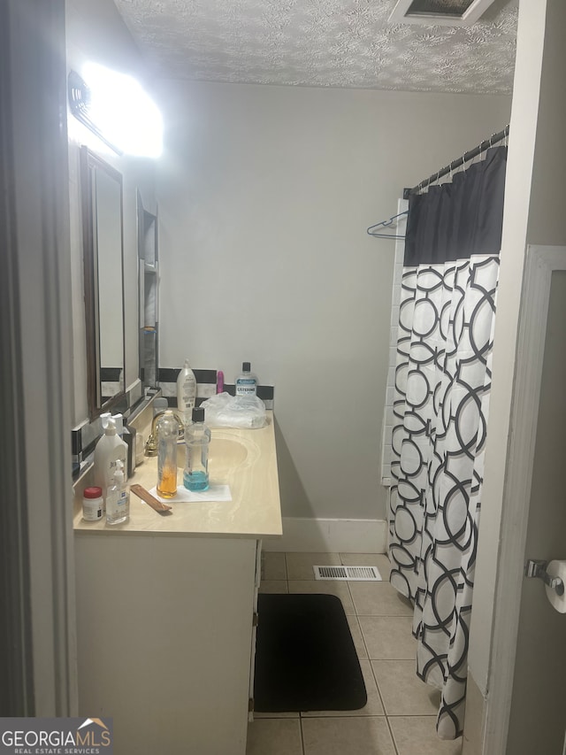 bathroom with tile floors, vanity, and a textured ceiling