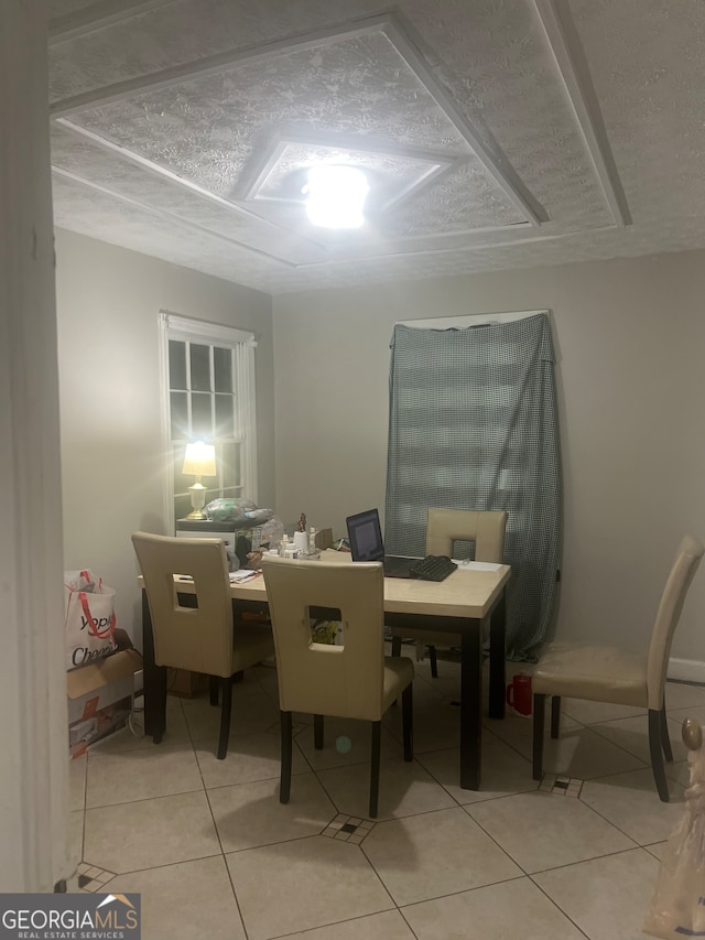 dining area featuring a textured ceiling and light tile flooring