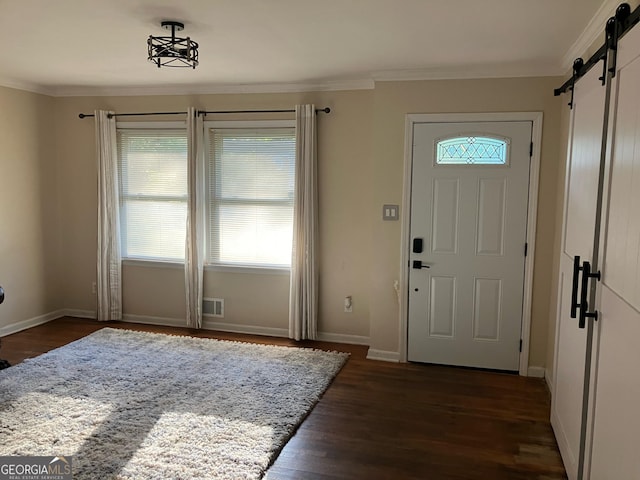 foyer featuring a barn door, dark hardwood / wood-style flooring, and ornamental molding