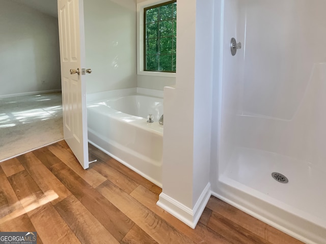 bathroom featuring hardwood / wood-style flooring and shower with separate bathtub