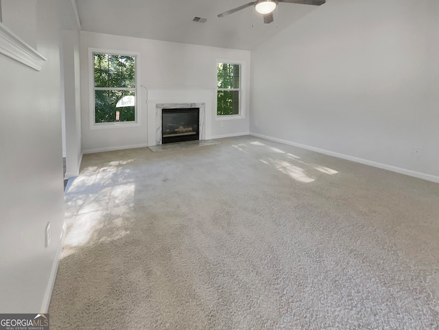 unfurnished living room with vaulted ceiling, ceiling fan, carpet, and a fireplace