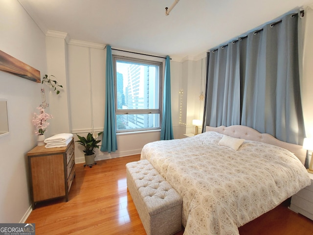 bedroom with light hardwood / wood-style flooring and crown molding