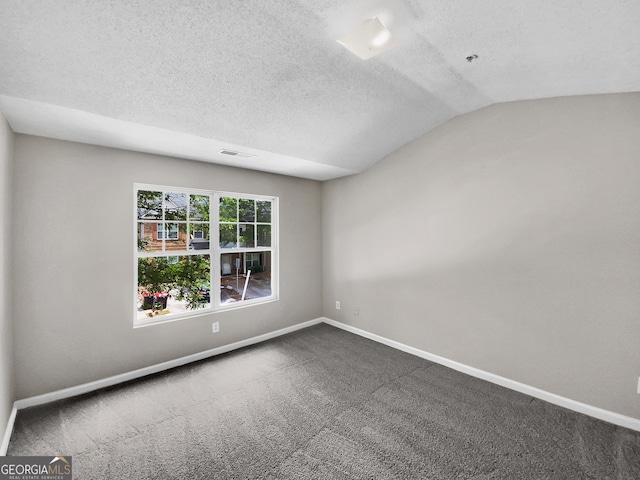 empty room featuring a textured ceiling, vaulted ceiling, and carpet