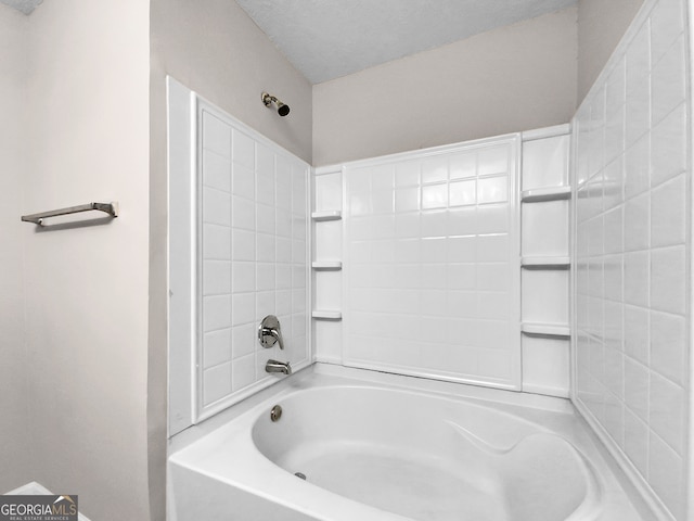 bathroom with a textured ceiling and bathing tub / shower combination