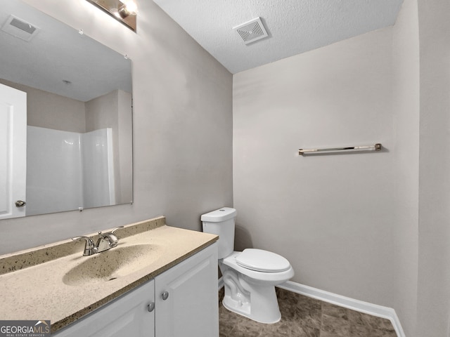 bathroom with a textured ceiling, vanity, tile floors, and toilet