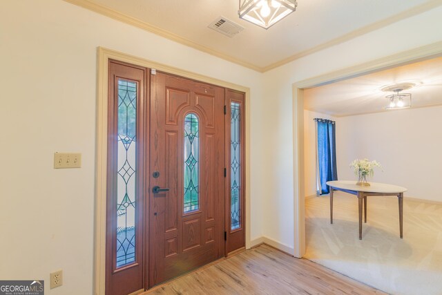 foyer featuring crown molding and light hardwood / wood-style flooring