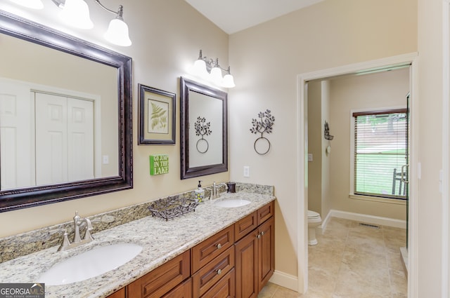 bathroom with vanity with extensive cabinet space, toilet, double sink, and tile flooring