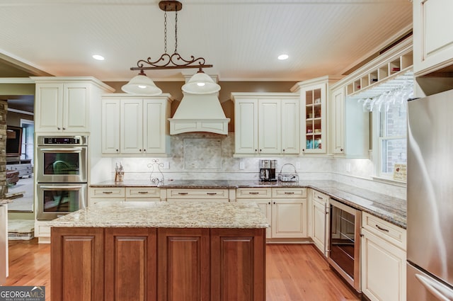 kitchen featuring appliances with stainless steel finishes, backsplash, wine cooler, pendant lighting, and light wood-type flooring