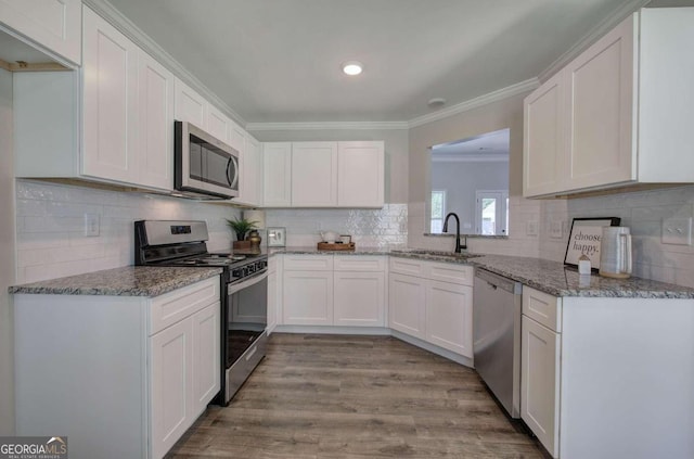 kitchen featuring crown molding, light wood-type flooring, stainless steel appliances, white cabinets, and sink