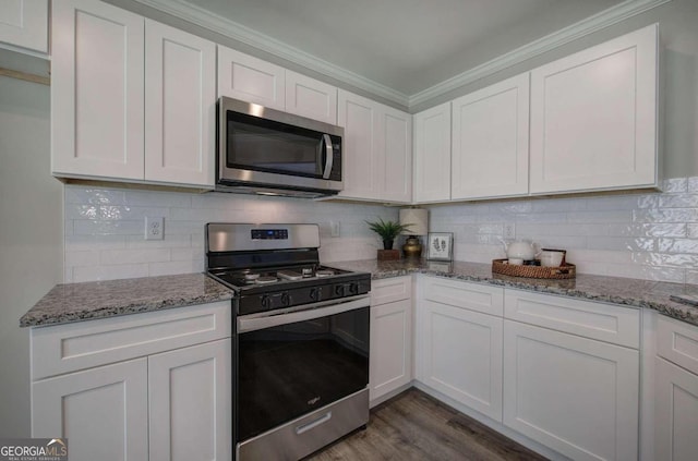 kitchen with appliances with stainless steel finishes, white cabinets, backsplash, and dark hardwood / wood-style floors