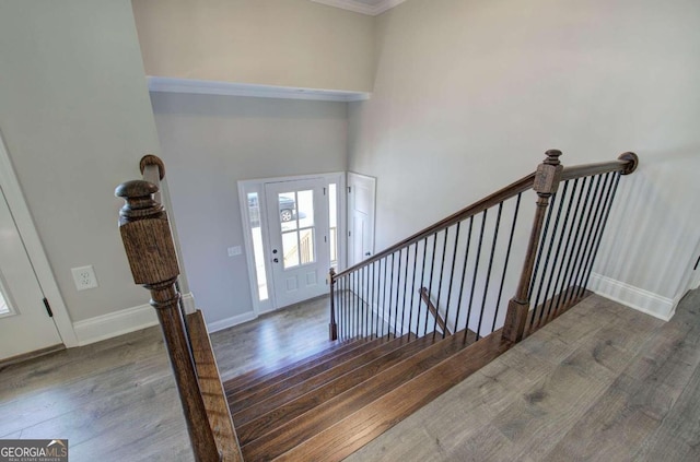 stairs featuring dark hardwood / wood-style floors, a high ceiling, and crown molding