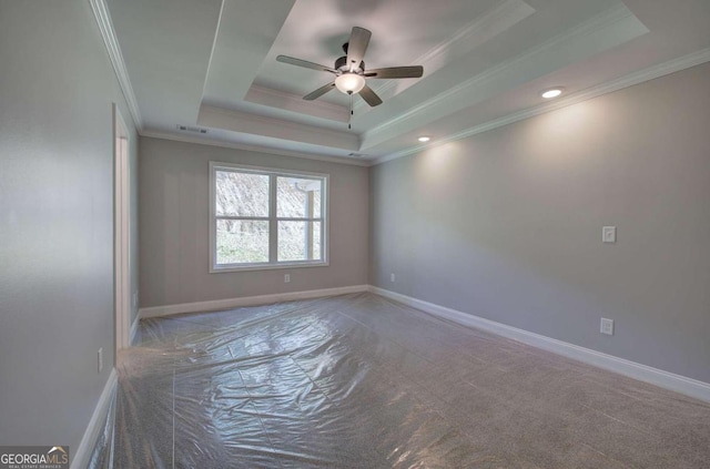 spare room featuring a tray ceiling, carpet floors, crown molding, and ceiling fan