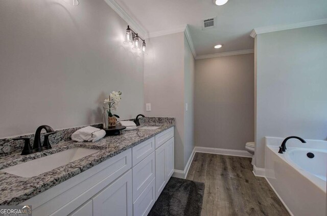 bathroom with dual vanity, toilet, hardwood / wood-style floors, ornamental molding, and a bath