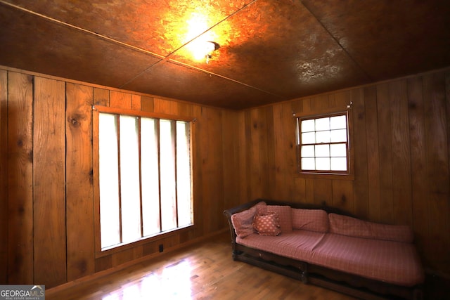 sitting room with wood walls, hardwood / wood-style flooring, and a healthy amount of sunlight