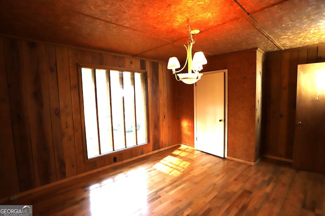 interior space with hardwood / wood-style floors, a notable chandelier, and wooden walls