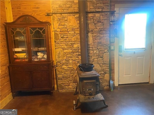 interior space featuring concrete flooring, wooden walls, and a wood stove