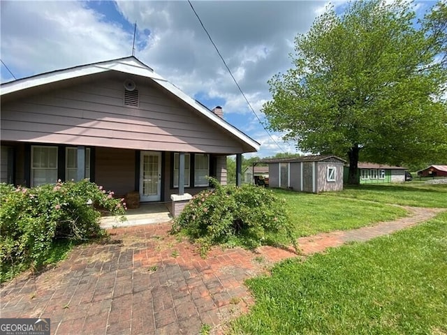 bungalow-style home featuring a front yard, a porch, and a storage shed