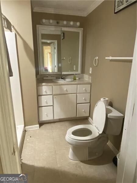 bathroom with tile flooring, ornamental molding, vanity, and toilet