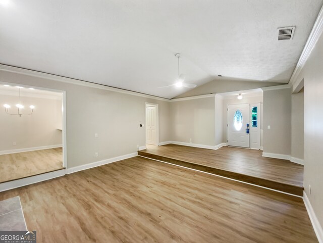 unfurnished room featuring hardwood / wood-style floors, vaulted ceiling, crown molding, and a notable chandelier