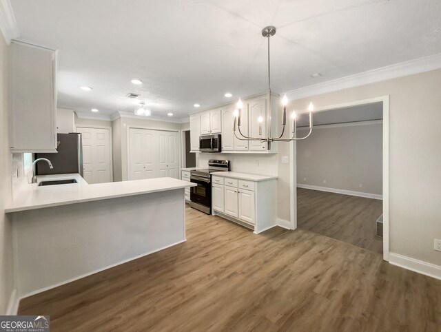 kitchen featuring appliances with stainless steel finishes, white cabinets, sink, ornamental molding, and hardwood / wood-style flooring