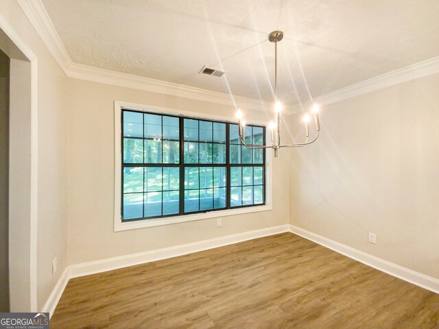 spare room featuring hardwood / wood-style floors, a notable chandelier, and crown molding