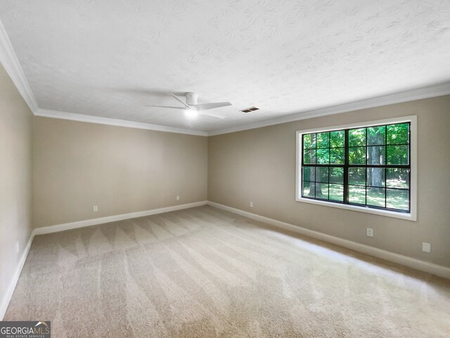 carpeted spare room featuring a textured ceiling, ceiling fan, and ornamental molding