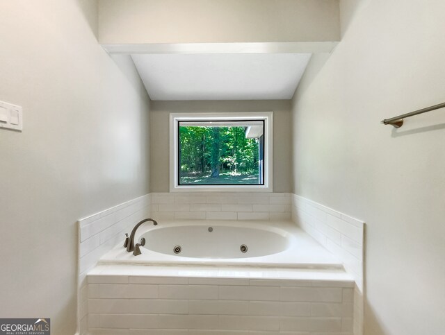 bathroom featuring lofted ceiling and tiled bath