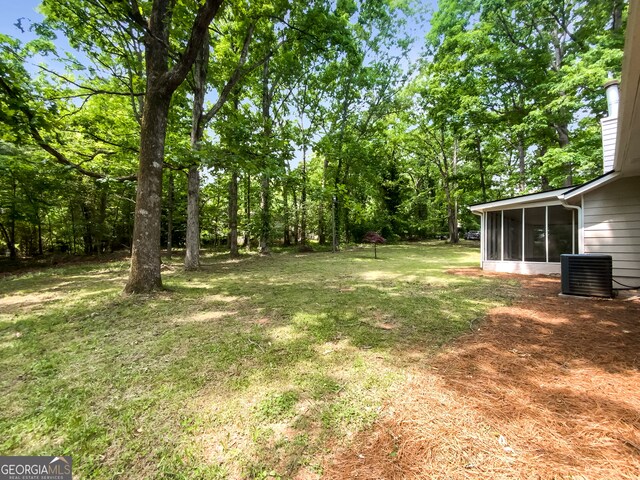 view of yard with central AC unit and a sunroom