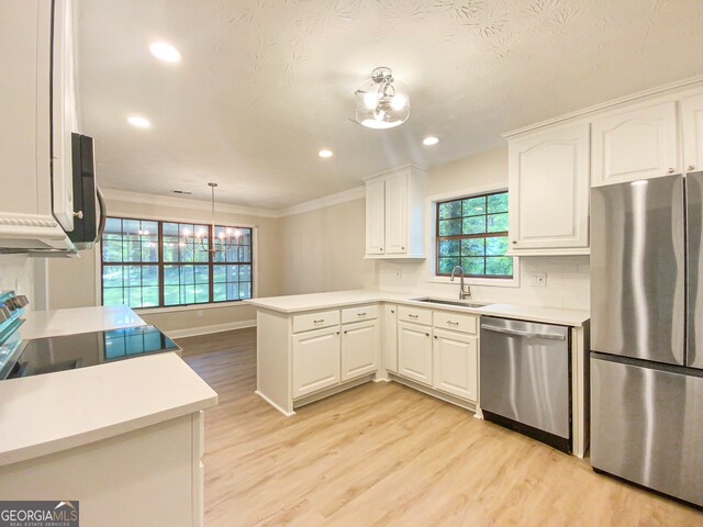 kitchen with sink, stainless steel appliances, light hardwood / wood-style floors, and kitchen peninsula