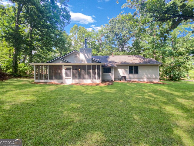 rear view of property featuring a sunroom and a lawn