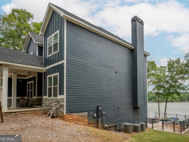 view of property exterior with central air condition unit and a water view