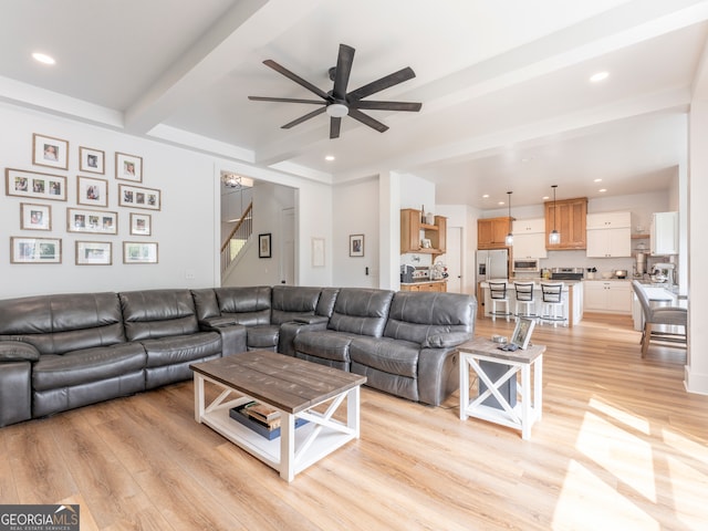 living room featuring beamed ceiling, ceiling fan, and light wood-type flooring