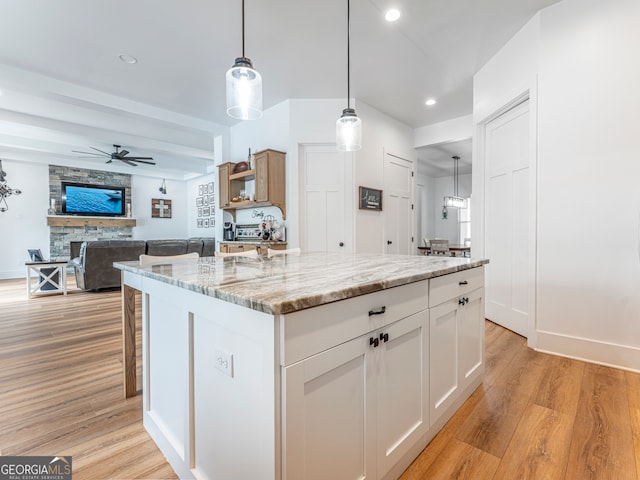 kitchen with a kitchen island, hanging light fixtures, white cabinetry, and light wood-type flooring