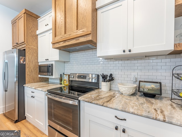 kitchen with tasteful backsplash, light hardwood / wood-style floors, stainless steel appliances, and light stone counters