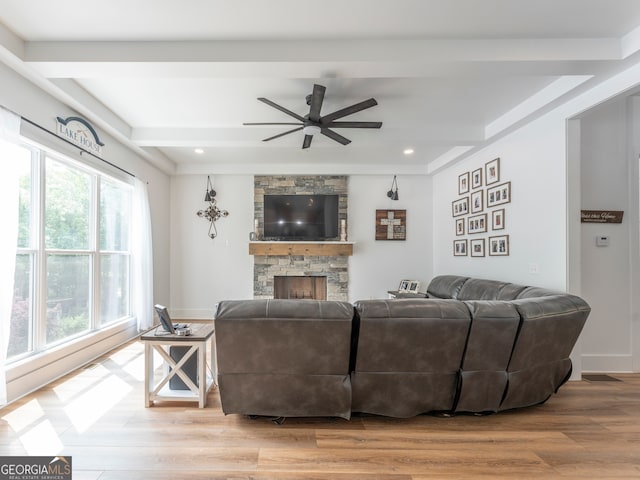 living room with light hardwood / wood-style floors, ceiling fan, a stone fireplace, and a wealth of natural light