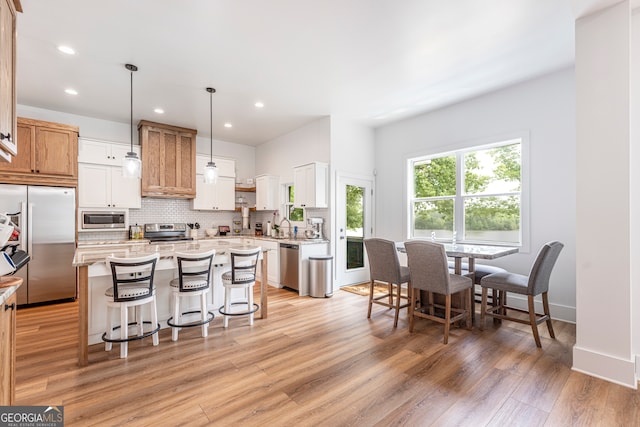 kitchen with a center island, tasteful backsplash, light wood-type flooring, pendant lighting, and built in appliances