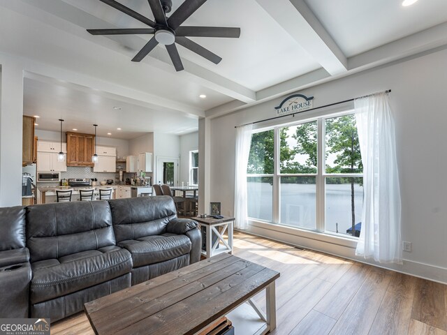 living room featuring beamed ceiling, light hardwood / wood-style flooring, and ceiling fan