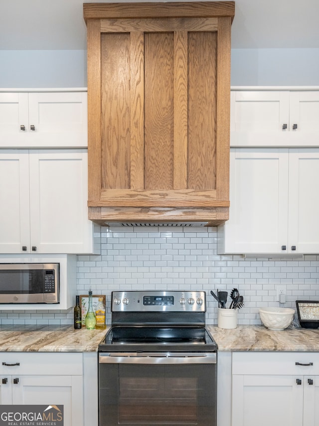 kitchen featuring tasteful backsplash, appliances with stainless steel finishes, white cabinets, and light stone counters