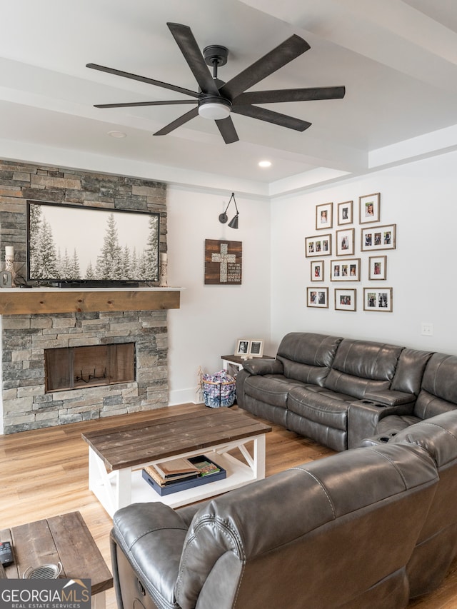 living room with hardwood / wood-style floors, ceiling fan, and a stone fireplace