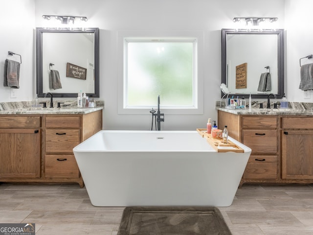 bathroom with a washtub and double sink vanity