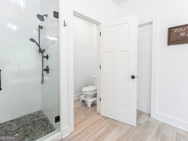 bathroom with an enclosed shower, hardwood / wood-style flooring, and toilet