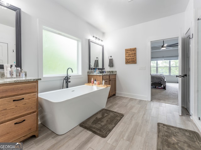 bathroom featuring ceiling fan, hardwood / wood-style floors, vanity, and a washtub