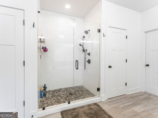 bathroom with a shower with door and hardwood / wood-style flooring