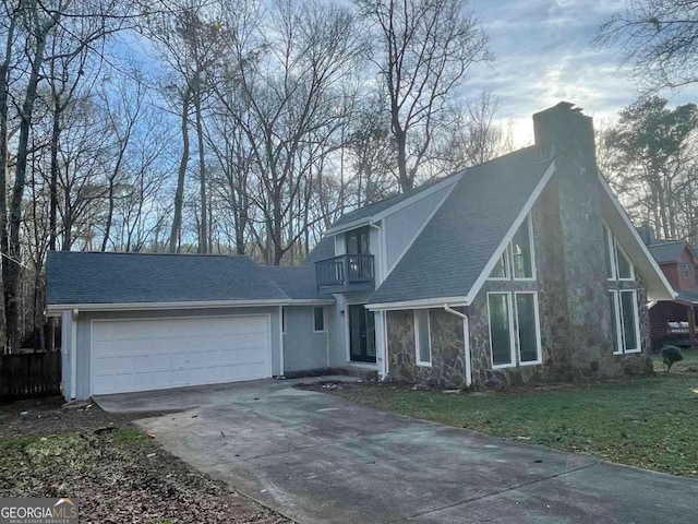 view of property featuring a garage, a balcony, and a front lawn