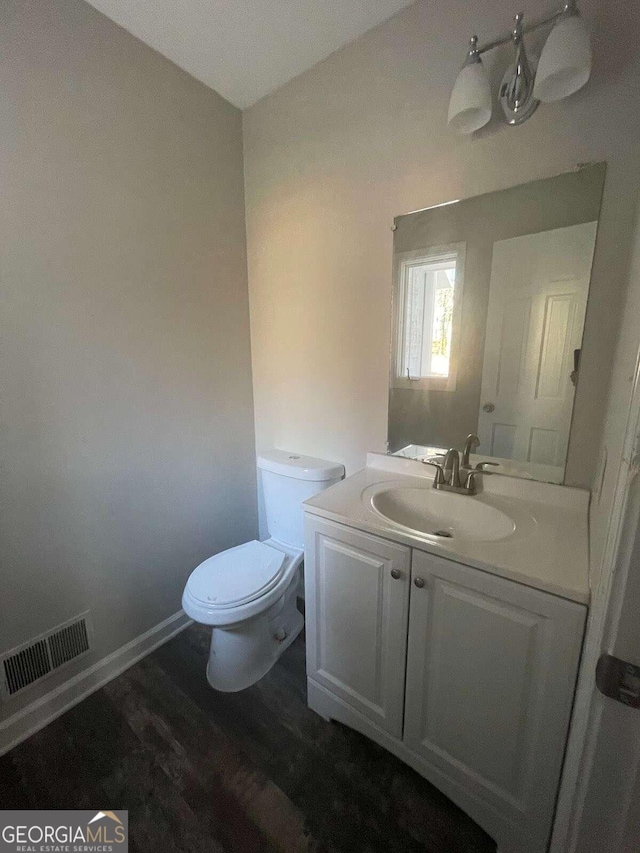 bathroom featuring vanity with extensive cabinet space, toilet, and hardwood / wood-style floors