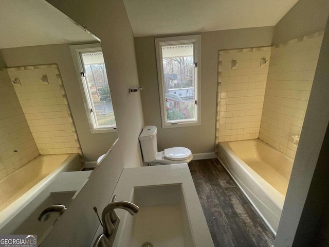 full bathroom with wood-type flooring, plenty of natural light, tiled shower / bath, and toilet