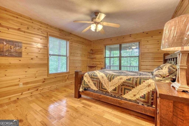 bedroom with light hardwood / wood-style floors and wooden walls