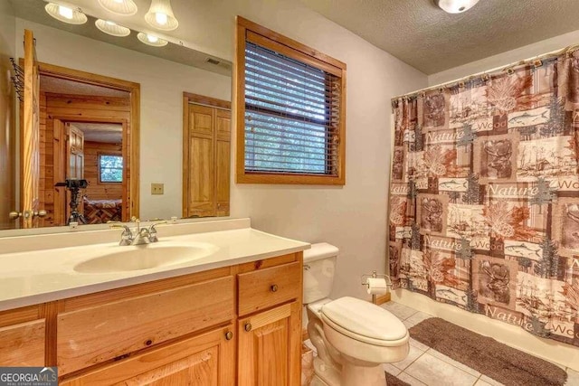 bathroom with a textured ceiling, tile floors, toilet, and vanity with extensive cabinet space