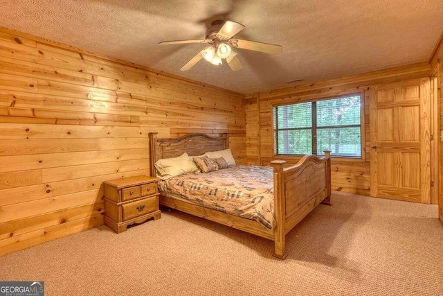 bedroom with a textured ceiling, wood walls, ceiling fan, and carpet flooring