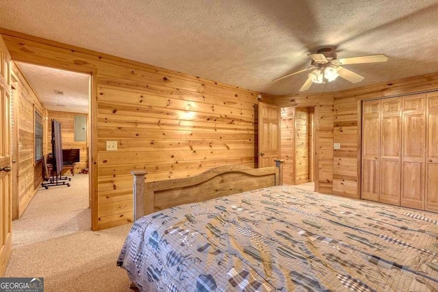 bedroom with light carpet, wood walls, ceiling fan, and a textured ceiling